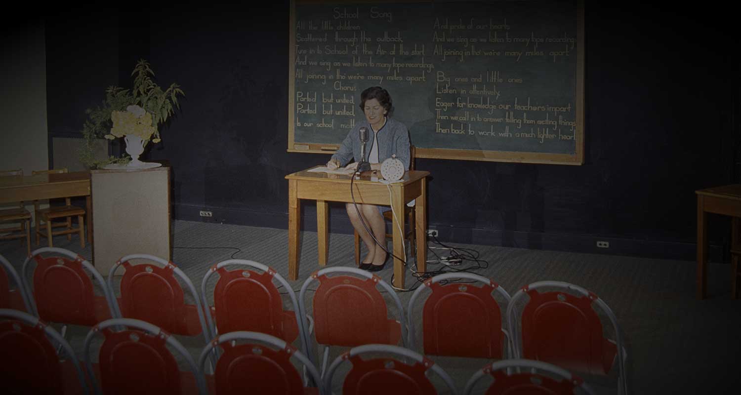 A teacher at the radio school speaks into microphone in an empty classroom.