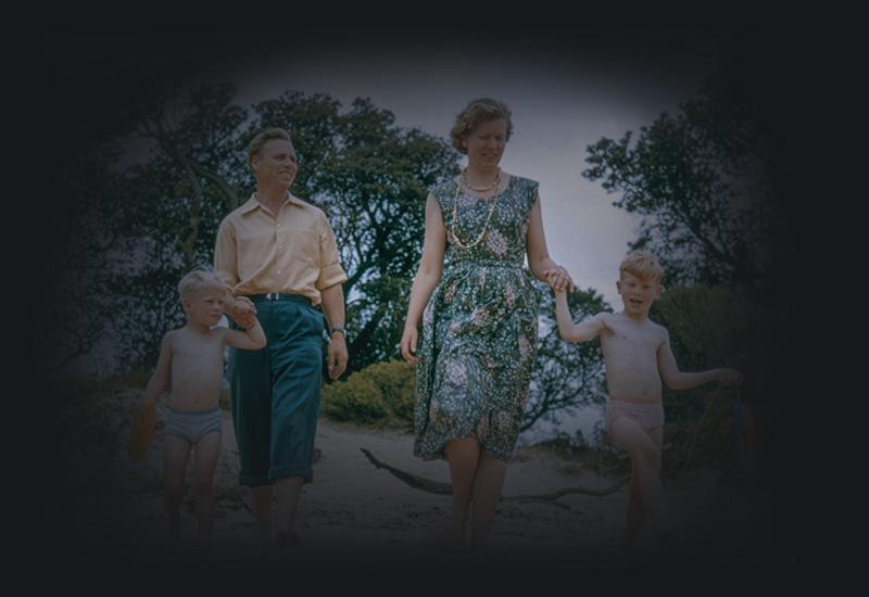 A mother, father and two children walking outside in the sun.
