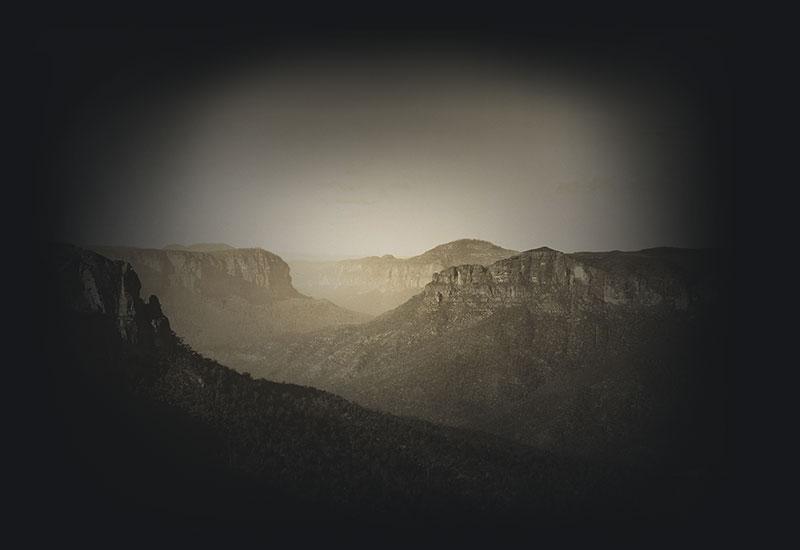 Forested valleys between table-top mountains with sandstone cliffs.
