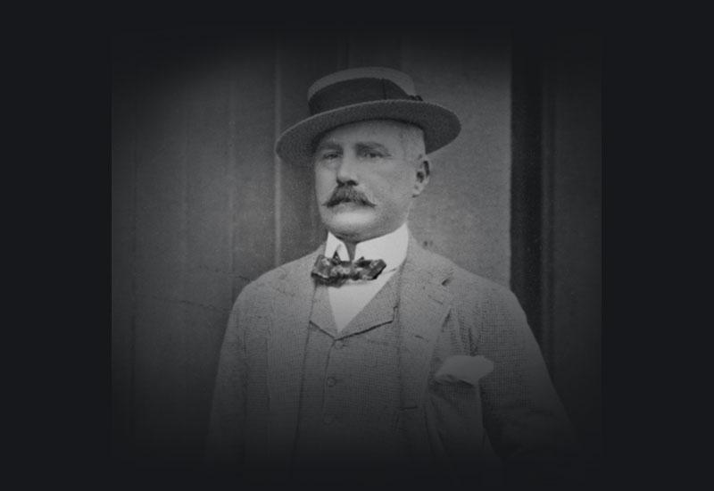 A man with a Moustache wearing a boater, bow tie and 3 piece suit.