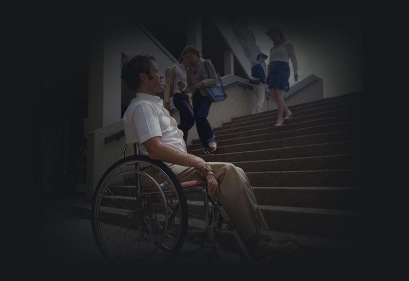 A man in a wheelchair contemplates stairs.