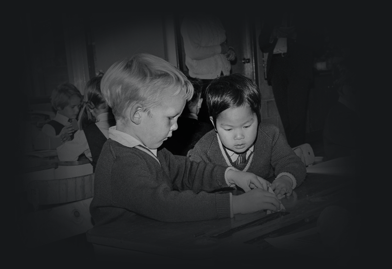 A Vietnamese war orphan and an Australian friend working at a desk in school.