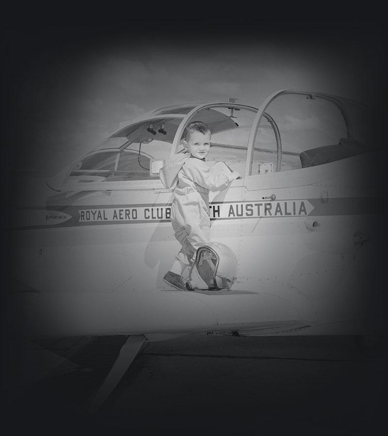 Young child with flight suit and helmet standing on an aircraft wing