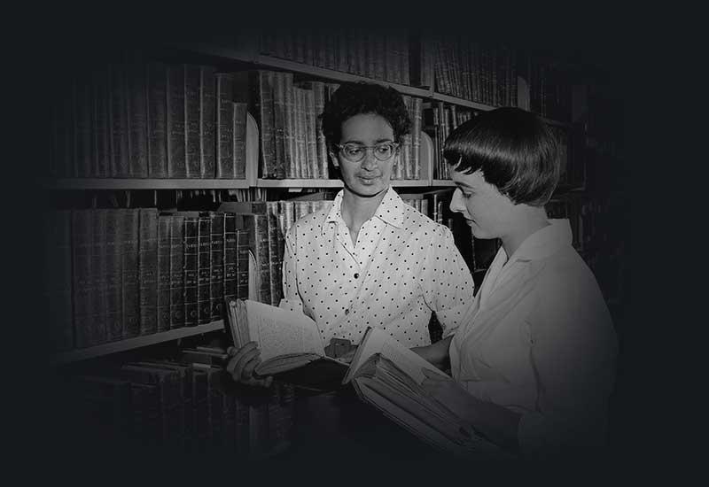 Miss Sadka (left), a Singapore historian, who is doing research work at the National Library talking to Assistant Librarian, Helen Hibberson