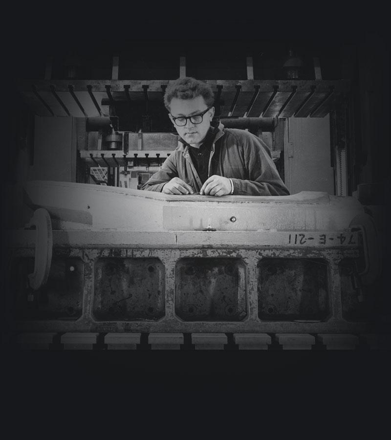 A man in overalls working on what could be an industrial steel press