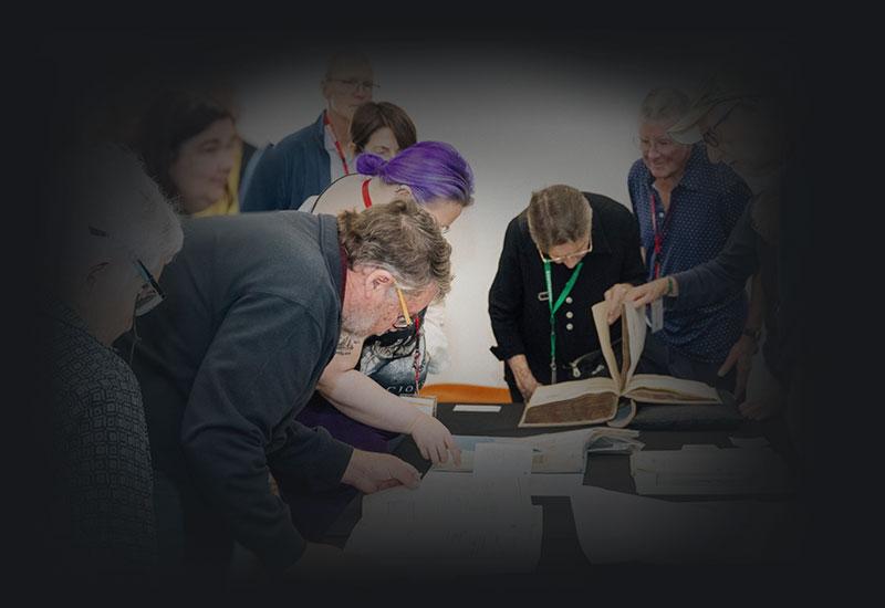 People viewing pages from archival files.