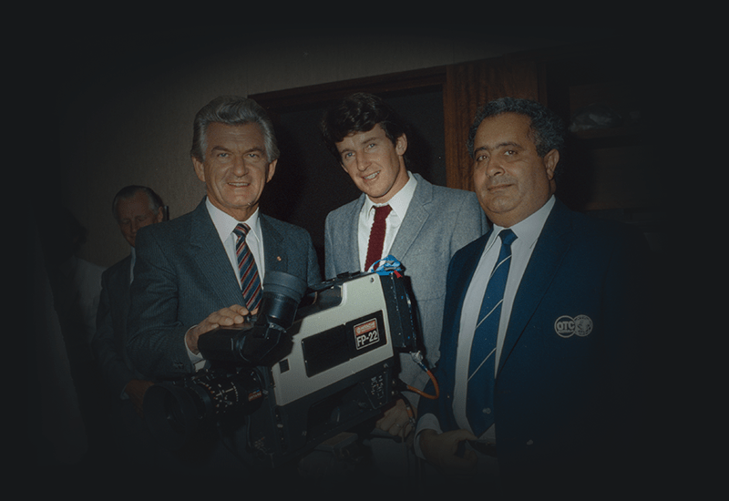 Bob Hawke with Overseas Telecommunications Commission officers with a video camera on timber tripod.