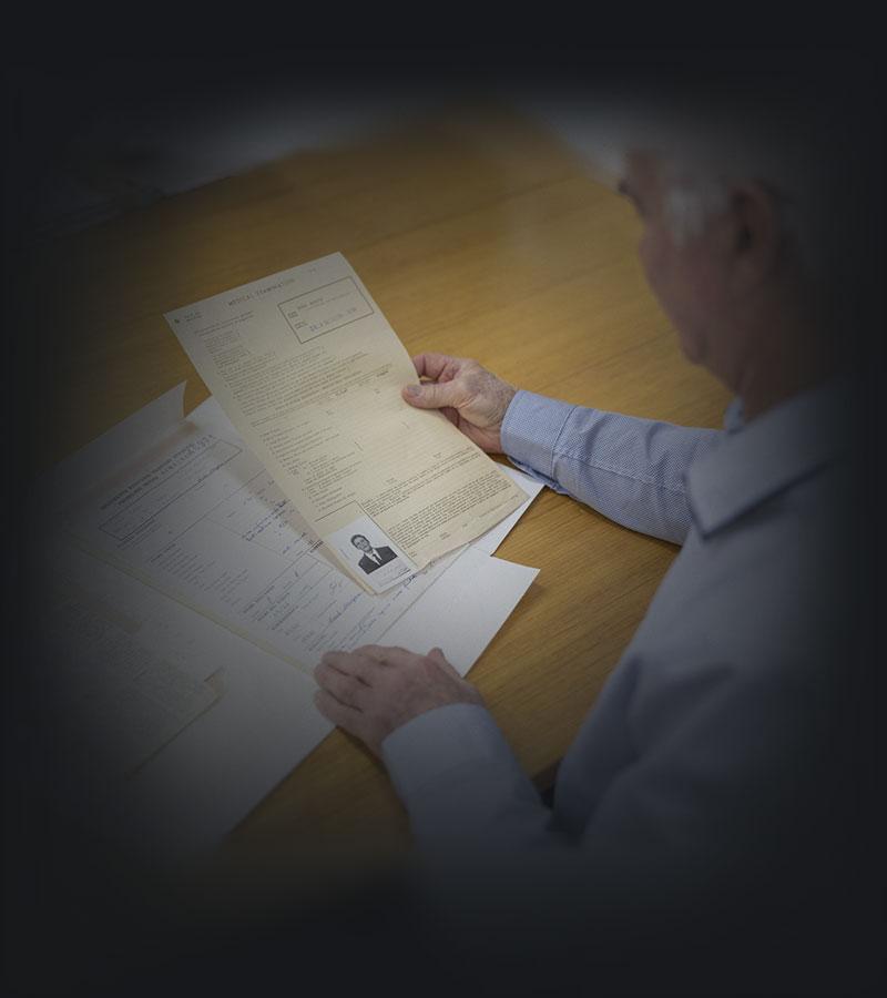 A man looking at a paper immigration record.