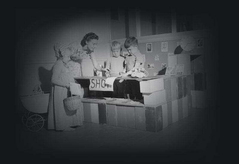 A woman and 2 children playing shop