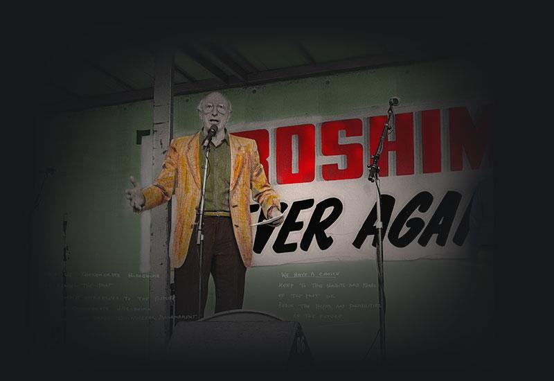 A man speaking in front of a banner: Hiroshima, never again