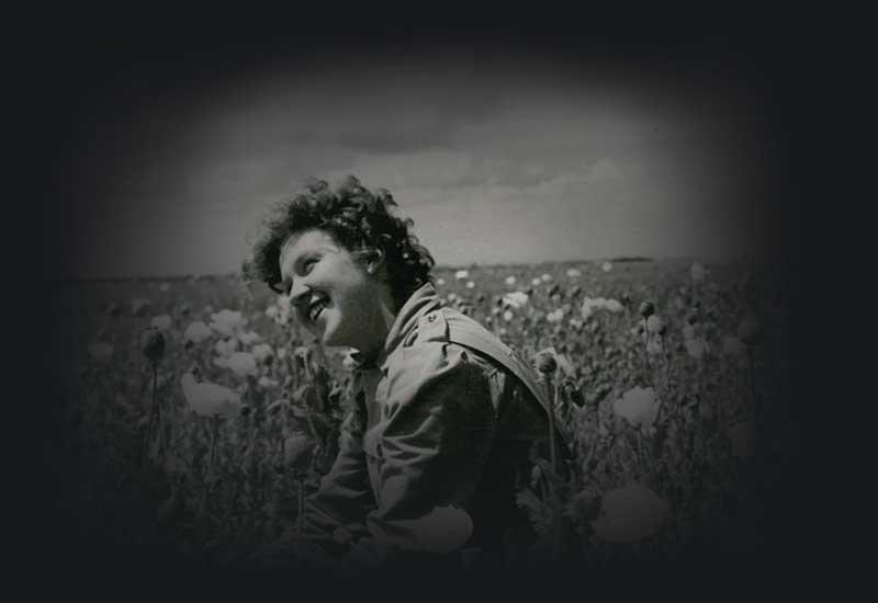 A woman smiling in a field of poppies. 