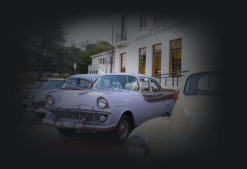 Holden cars from the 50s and 60s parked next to the National Archives of Australia, Parkes
