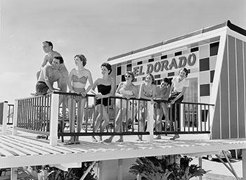 8 people mostly wearing swimwear standing on a deck at the Eldorado Motel.