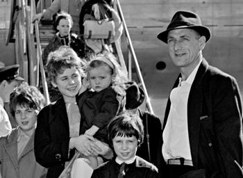 A father and four children standing in front of a migrant ship. 