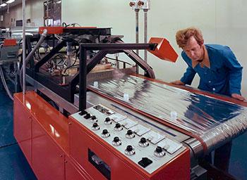 A man inspecting foil wine bags on a machine during production