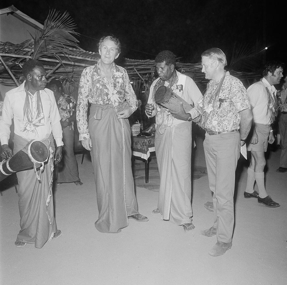 Malcolm Fraser standing with two Torres Strait Island men wearing sarongs.