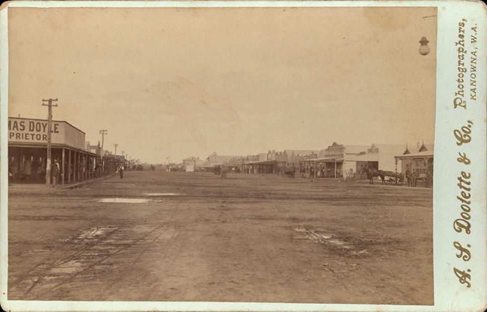 Wide dirt main road and timber buildings with verandahs.