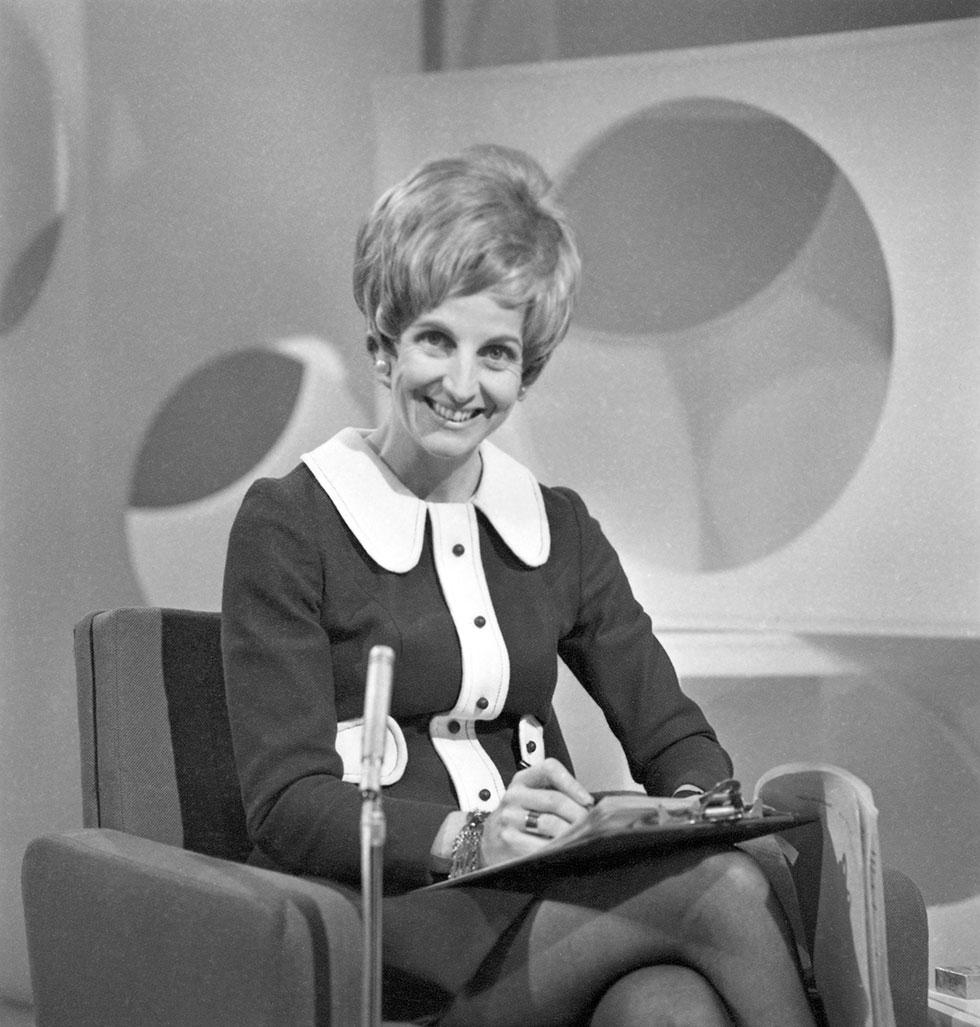 A woman seated near a microphone.