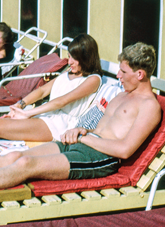 Man and woman sunbathe on beach chairs on the balcony of the Beachcomber Hotel.
