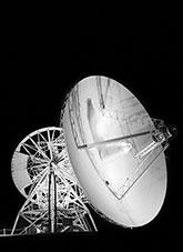 Radio telescope support structure and dish illuminated at night.