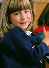 A child with a short haircut smiling at the camera. 