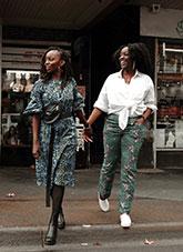 Two women stepping off a footpath holding hands