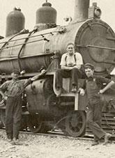 Men leaning against and sitting on a locomotive.