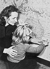A woman and child crouched beside a map pointing at a shipping route from Europe to Australia.