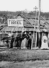 Horse with cart and people standing outside Rock Cashel Hotel.