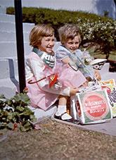 2 young smiling children sitting on a step holding show sample bags.