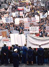 Protestors holding banners before a police blockcade.
