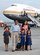 A Vietnamese family standing on the tarmac with a Qantas 747 in the background.