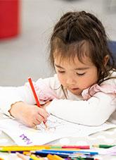 A child drawing with a coloured pencil.