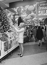 Industry - Shops - Girl selects Christmas decorations for tinsel tree.