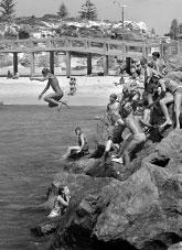Children jumping from rocks into the sea.