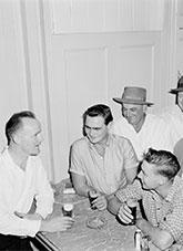 Men holding glasses of beer gathered at a bar