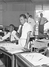 A Papuan Member, Mr Mahuru Rarua-Rarua, addressing the Papua and New Guinea Legislative Council at Port Moresby. To his left is a New Guinean Member, Mr Simogun Peta of the Sepik District, and on his right, Mr John Vuia, a prominent leader of the Tolai people in the Gazelle Peninsula area of New Britain
