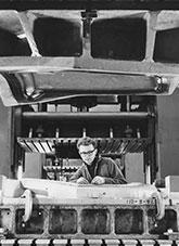 A man in overalls working on what could be an industrial steel press