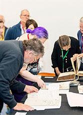 People viewing pages from archival files.