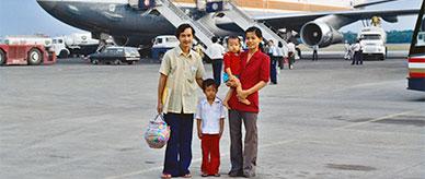 2 adults with young children standing on the tarmac with a Boeing 747 aircraft behind them.