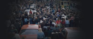 People crowding around cars and a tram