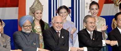 Women wearing National dress stand behind world leaders holding hands