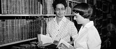 Miss Sadka (left), a Singapore historian, who is doing research work at the National Library talking to Assistant Librarian, Helen Hibberson