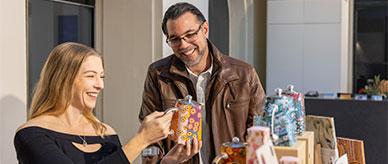 2 people smiling while looking at a tea pot