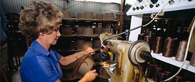 A woman sewing an Akubra hat band to a hat