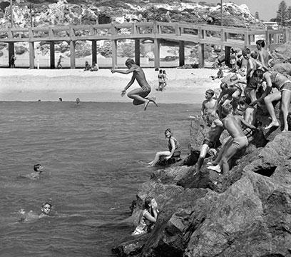 Children jumping from rocks into the sea.