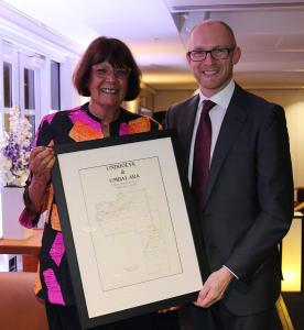 2 people holding a framed map between them.