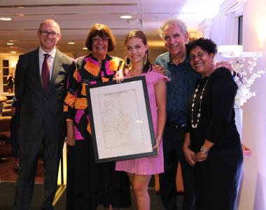 five people standing with a framed map.