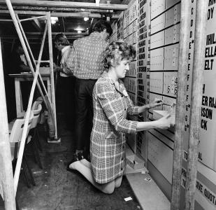 A woman kneeling to adjusting a tally board.