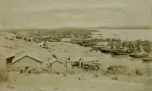 Small timber buildings near moored sailing boats.